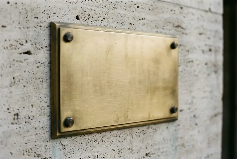 Placa de latão escovado sem inscrição em parede de travertino